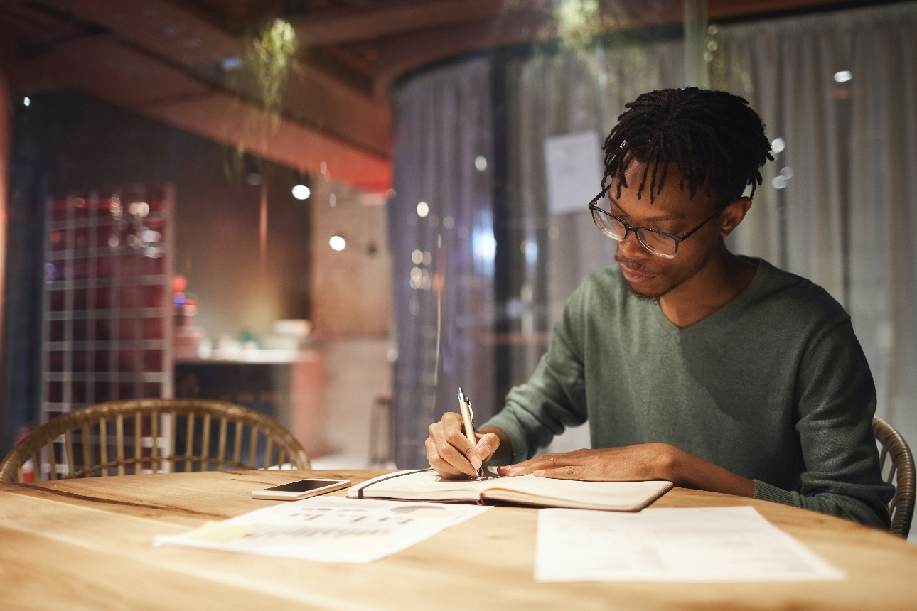 man sat writing in in his home in a pad