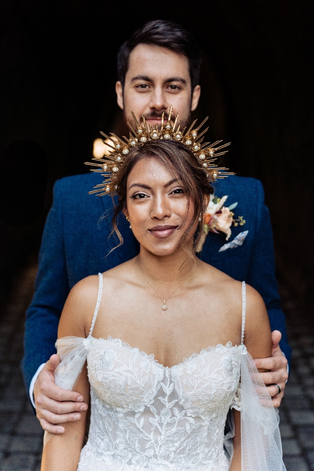 Bride in forground with starburst headpiece, groom in background